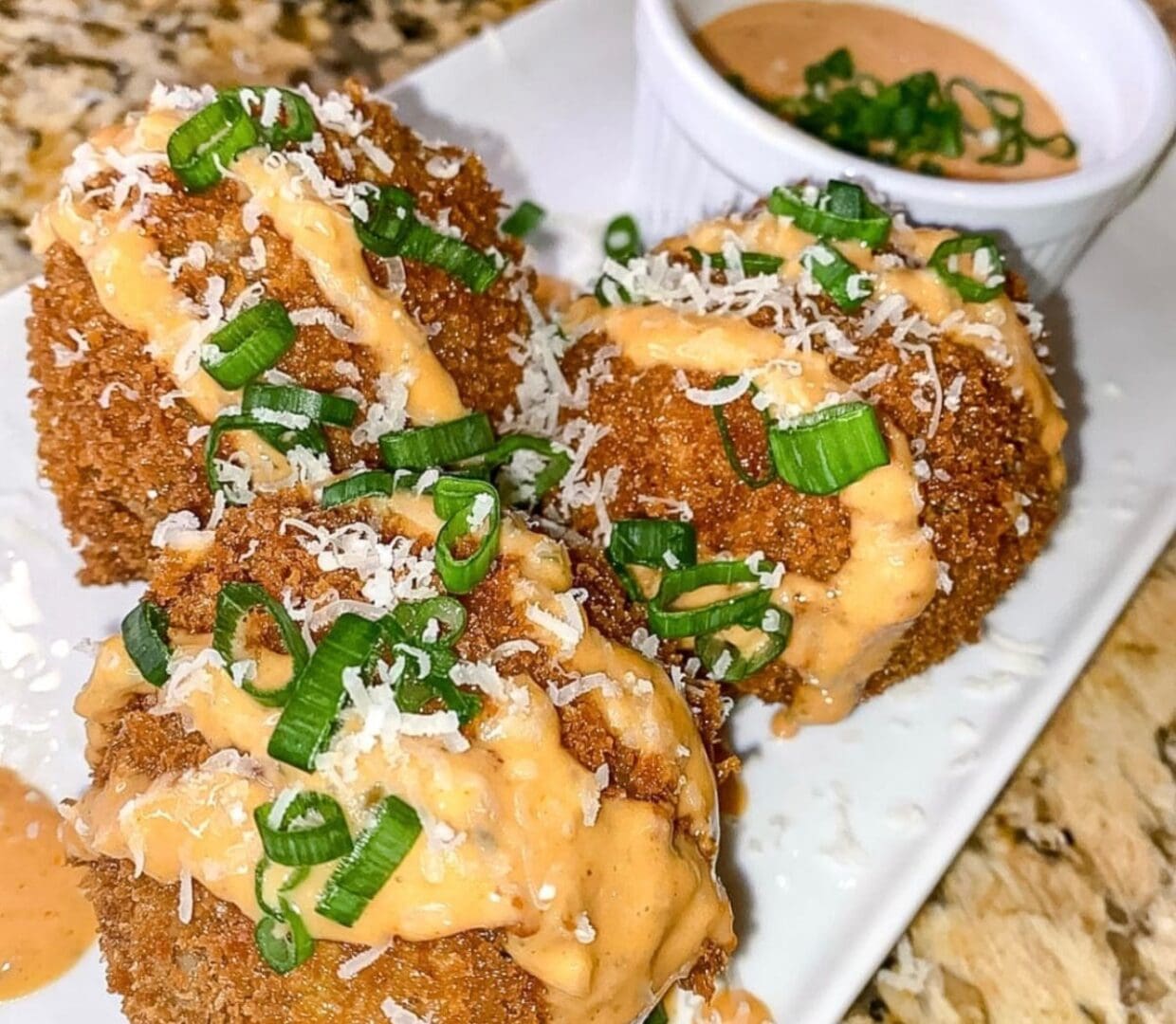 Loaded baked potatoes topped with cheese, sour cream, green onions, and a side of dip.