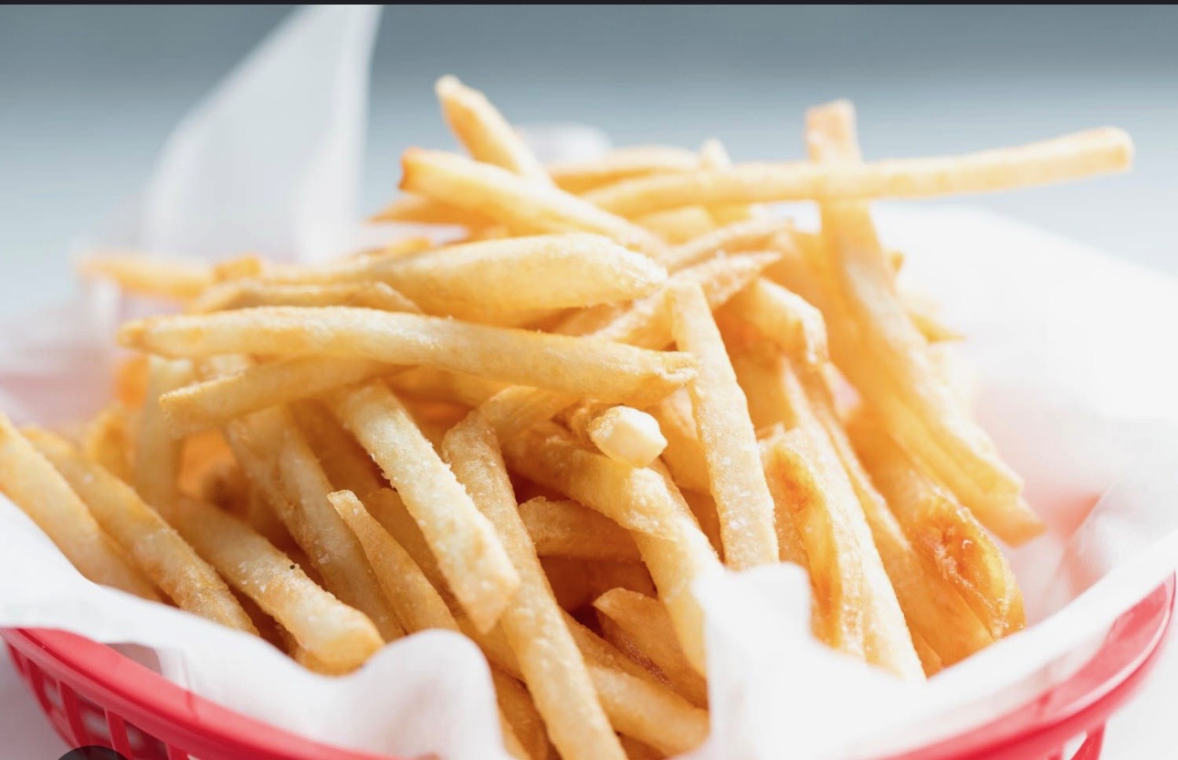 A close-up of crispy French fries in a white container.
