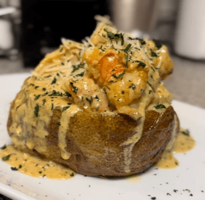 Loaded baked potato topped with creamy shrimp and herbs.